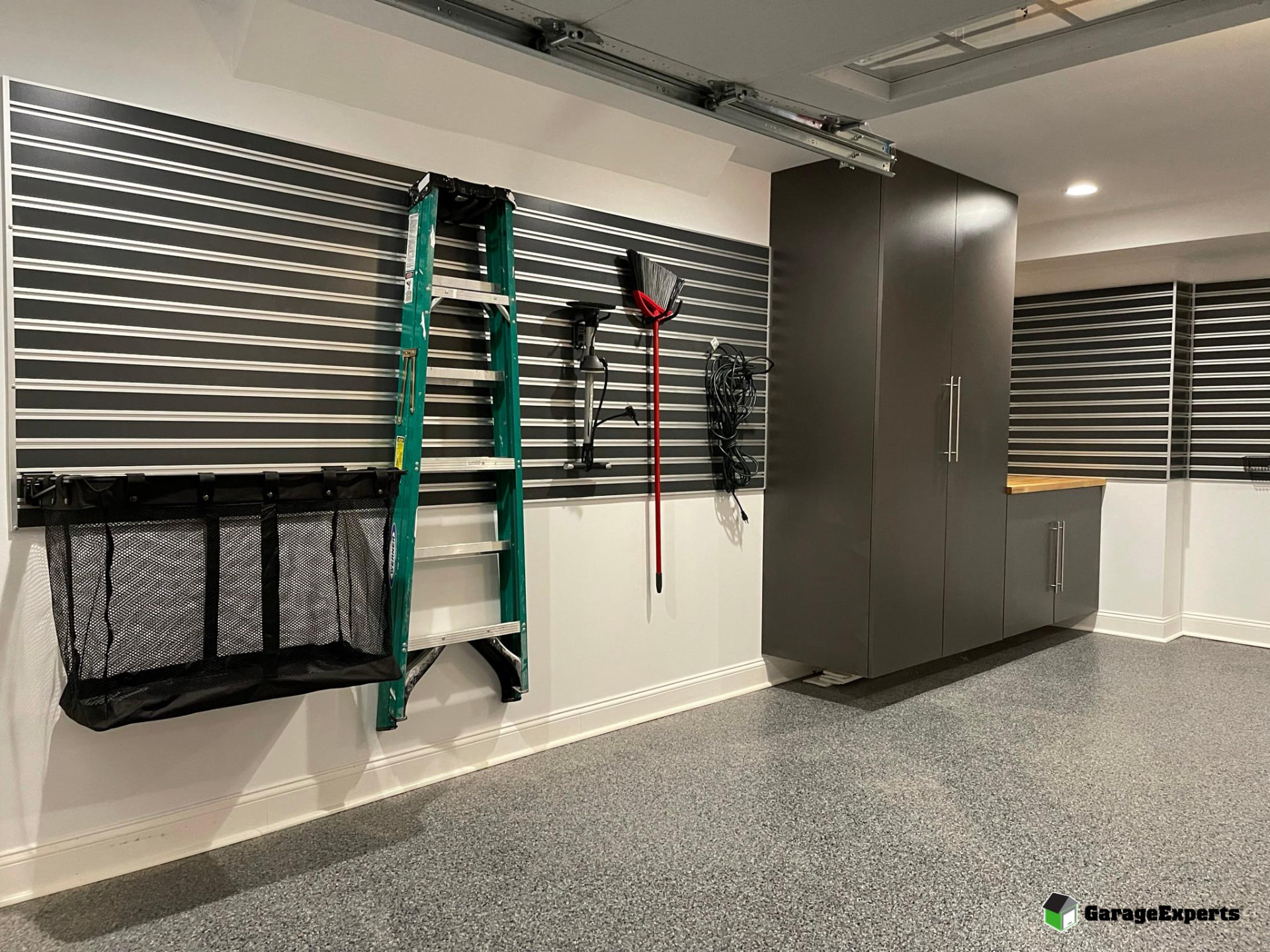 Slatwall organization system with tools and equipment stored beside custom cabinets