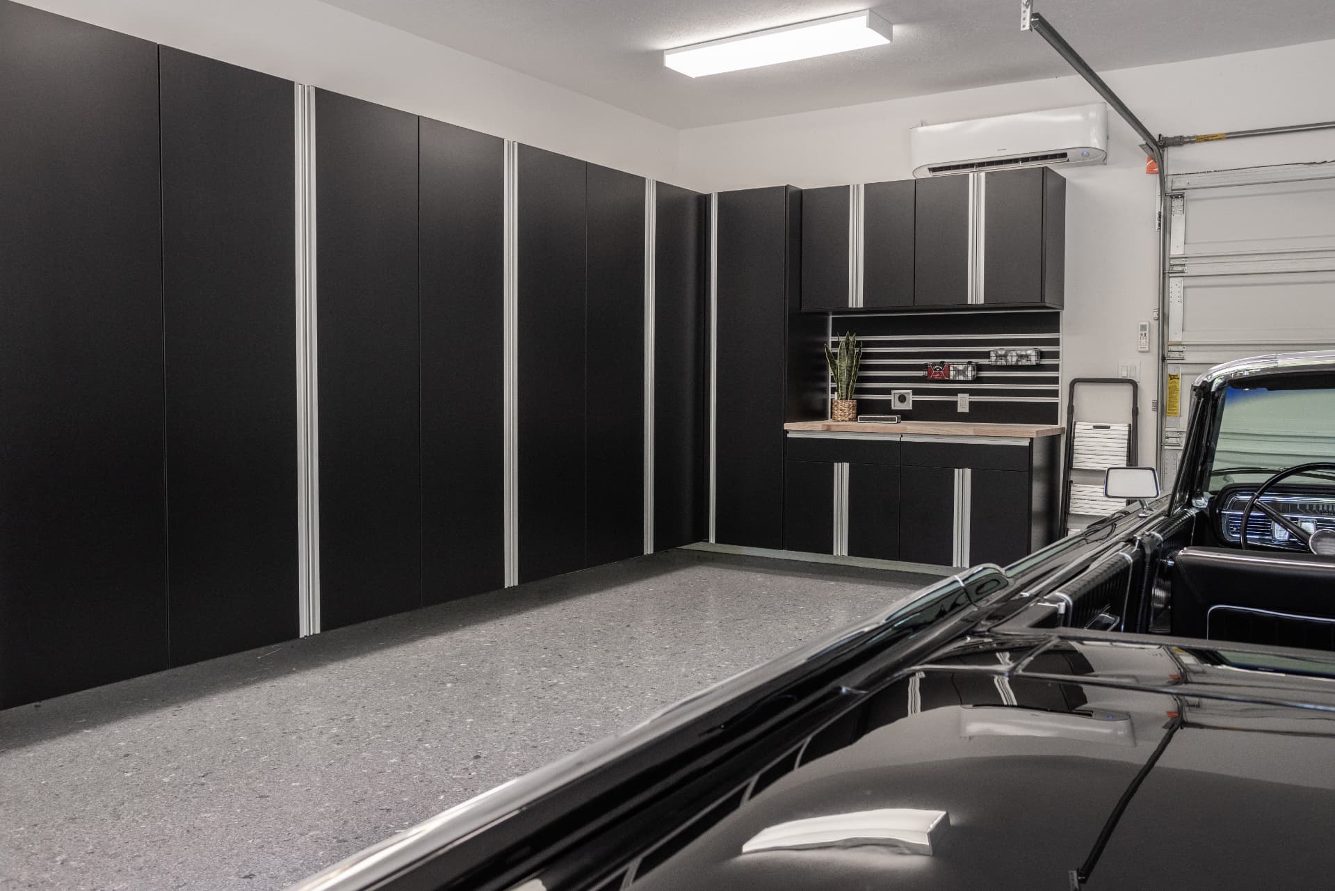 Black custom garage cabinets installed along a garage wall with a Basalt flake floor