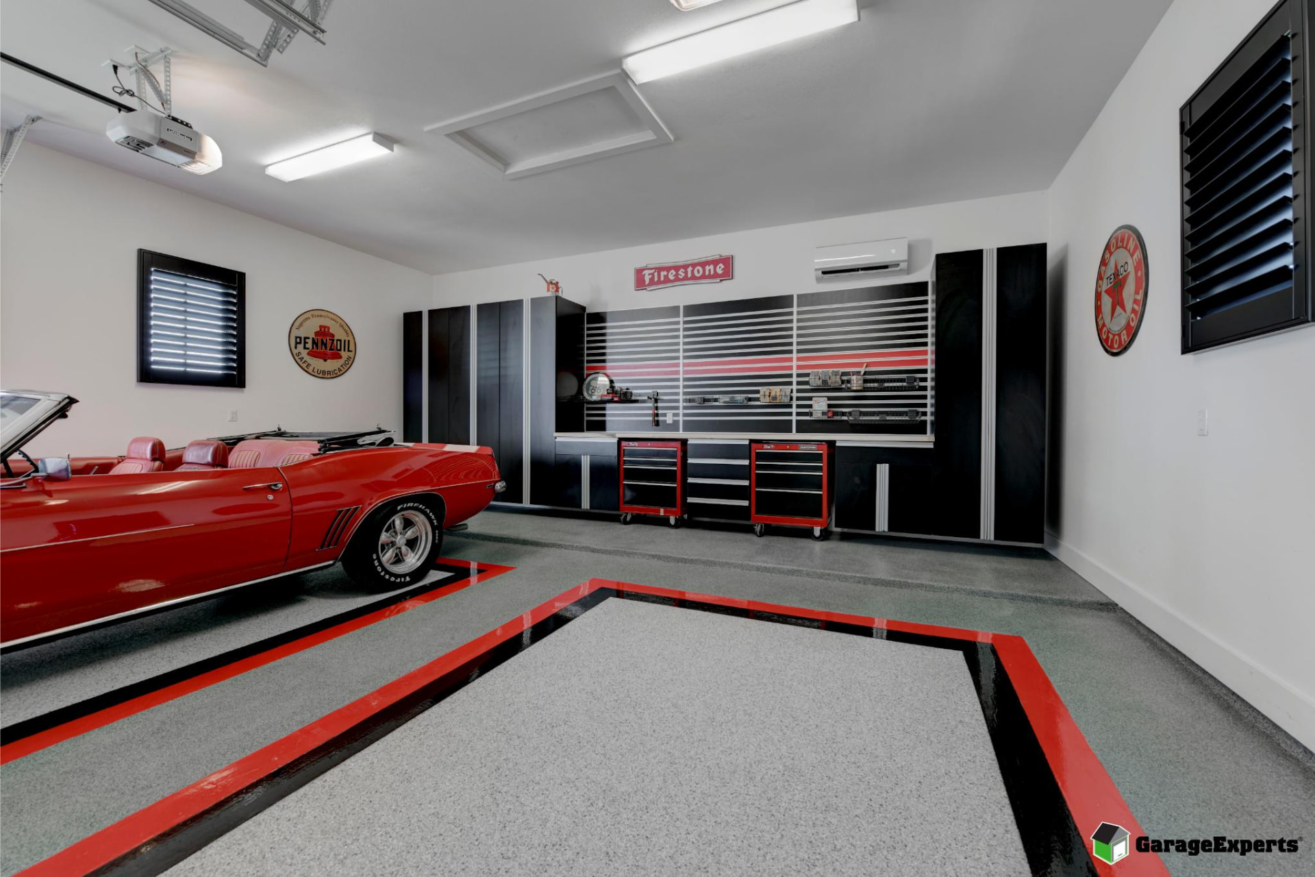 Custom bordered garage floor coating with black cabinets and a red vintage convertible